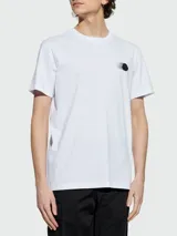 Remera de algodón blanca de corte clásico, con cuello redondo y mangas cortas. Presenta un pequeño logo circular estampado en el pecho con efecto de movimiento.