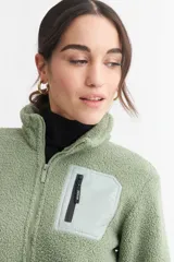 Campera negra de corderito con cuello alto, cierre frontal con cremallera, bolsillo de parche en el pecho y bolsillos laterales.