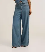Pantalón de jeans de tiro alto, corte ancho (wide leg/pantalona) en tono celeste desgastado. Presenta cierre y botones frontales, trabillas en la cintura y bolsillos delanteros y traseros.