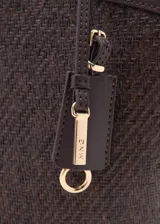 Bolso tipo shopper de tamaño mediano confeccionado en tejido de fibra natural con detalles en poliuretano. Cuenta con dos asas largas para llevar al hombro, cierre de cremallera superior, bolsillo interior y un charm colgante decorativo con herrajes dorados.