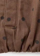 Chaqueta bomber de algodón color marrón con estampado de lunares, cuello embudo, manga larga, bolsillos laterales y cierre oculto con cremallera y botones a presión.