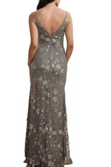 Vestido largo de fiesta color gris con bordados florales en tono rosado. Presenta escote en V con tirantes finos, diseño entallado en la cintura con drapeado y falda con tajo lateral profundo.