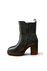 Bota alta de cuero negro con plataforma track, taco ancho y dos tiras con hebillas metálicas plateadas en el lateral.