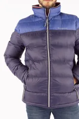 Campera puffer de diseño color block, con parte superior en azul vibrante y parte inferior en azul oscuro. Presenta cuello elevado, cierre frontal completo con cremallera, bolsillos laterales con cierre y logo de la marca estampado en el pecho.