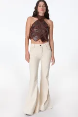 Pantalón de jean azul oscuro, corte acampanado (flare) de tiro alto, con costuras visibles en contraste y bordados tonales en la parte inferior de las piernas. El ruedo es deshilachado.