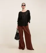 Blusa de punto color dorado, de acrílico y viscosa, con escote redondo, manga larga y sisa raglán. Tiene una malla con lámina metálica.