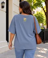 Remera de manga corta color celeste, de corte oversize, con un pequeño parche estampado con flores y la inscripción "Wild Soul" en la parte superior de la espalda.