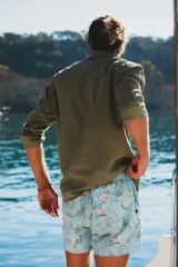 Short de baño color celeste con estampado botánico de hojas y flores en tonos verdes, naranjas y violetas. Cuenta con cintura elástica, bolsillos laterales y un bolsillo trasero con etiqueta de la marca.