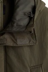 Campera parka acolchada repelente al agua y rompevientos, con cuello alto, capucha ajustable, cierre frontal con solapa y bolsillos frontales tipo parche y calientamanos.