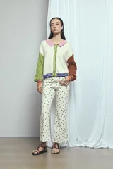 Cardigan de punto color marrón, con cuello vuelto, cierre frontal de botones y detalles de ribetes a rayas en los puños, la cintura y la botonera. Las mangas presentan un diseño tejido en relieve con textura de ochos.