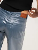 Pantalón de jean elastizado azul con terminación metalizada, corte wide leg, tiro medio, cierre delantero con botón, bolsillos laterales y traseros.