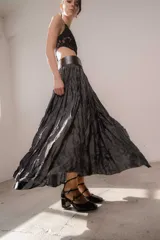 Pollera larga de tejido texturizado con efecto arrugado y acabado satinado, de color gris oscuro, con pretina ancha y silueta acampanada.