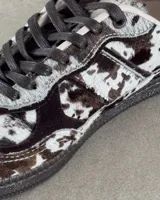 Zapatillas deportivas de cuero vacuno con estampado animal print de vaca en blanco y marrón.