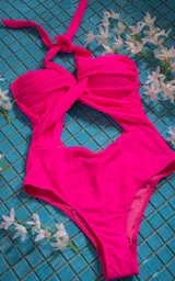 Traje de baño enterizo fucsia con escote halter, abertura en el abdomen y espalda descubierta.