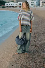 Bolso de hombro confeccionado en denim con efecto deslavado, diseño fruncido en los laterales con tiradores ajustables y asa de hombro combinada con cadena metálica plateada. Cuenta con cierre de cremallera y bolsillo interior.