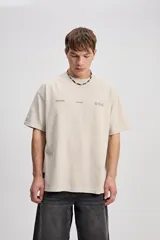Remera oversize de color azul marino, de manga corta y cuello redondo. Presenta un diseño estampado en la espalda con la inscripción "Boundless Art", un gráfico circular abstracto y textos adicionales.