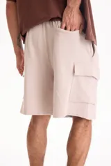 Bermuda cargo de felpa sin friza, color beige, con cintura elástica y bolsillos laterales con solapa.