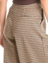 Pantalón de tiro alto con diseño wide leg y cintura elástica. Presenta un estampado de cuadros tipo gales en tonos marrones y negros, con bolsillos funcionales en la parte delantera.