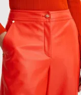 Pantalón recto de cuero sintético color naranja, con cierre frontal con botón y cremallera.