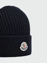Gorro de lana azul marino con textura acanalada y logo de la marca Moncler bordado en el frente.