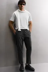 Pantalón negro de entrenamiento slim fit confeccionado en tejido técnico ligero y elástico con estructura. Cuenta con cintura elástica ajustable con cordón, bolsillos frontales y trasero con cierre de cremallera, y bajo ajustable con cremallera en laterales.