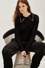 Sweater negro de punto calado con cuello polo decorado con apliques de piedras brillantes de colores. Presenta mangas largas con puños ajustados y un diseño elegante.