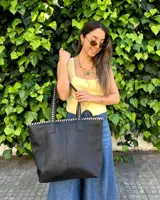 Bolso shopper grande de cuero negro, confeccionado a mano, con costuras artesanales visibles en contraste color crudo alrededor de la boca y en las asas.