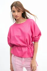 Blusa color salmón de manga tres cuartos con leve volumen, largo hasta la cadera y cinto extraíble en la espalda.