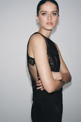 Vestido largo de corte recto con cuello redondo y diseño sin mangas. Presenta un cuerpo superior confeccionado en tejido mesh con aplicaciones de encaje floral a tono y una falda fluida de viscosa. Incluye cierre posterior con botones forrados.