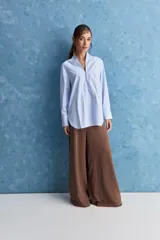 Camisa de calce relajado color celeste, con escote en V y cuello mao, mangas largas y largo extendido.