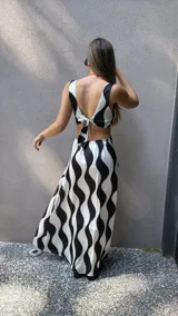 Vestido largo de tela sedosa con estampado de ondas verticales en blanco y negro, escote en V, cut out en la cintura, espalda regulable con lazo y elástico, y tajos laterales.