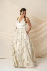 Vestido largo de fiesta color champagne, con corpiño tipo corsé de crepe de seda y falda amplia de organza con lurex dorado. Incluye bolsillos laterales.