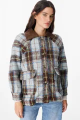 Chaqueta de corte holgado con estampado de cuadros en tonos beige, marrón y amarillo. Presenta cuello camisero en pana marrón, cierre frontal con botones y mangas largas con puños abotonados.