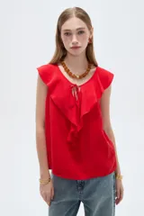 Blusa de viscosa color rojo, sin mangas, con cuello redondo y volados alrededor del escote que descienden por el frente. Presenta diseño holgado y cordones para atar en el centro.