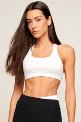 Top deportivo blanco de poliamida con diseño de espalda nadador, breteles medios y banda elástica inferior para mayor soporte. Cuenta con forro interno y entrada para copas removibles.