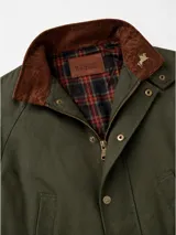 Campera tipo encerada de corte clásico para hombre, en color bordó, con cuello alto, cierre frontal con botones a presión metálicos y solapa, bolsillos frontales superiores ribeteados y bolsillos inferiores grandes con solapa y botón.