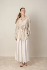 Camisa larga italiana color crudo, de calce holgado, con lazo en la cintura con flor y mangas largas con presilla para sujetar.