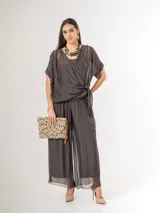 Pantalón de seda italiana con forro de viscosa elastizada, de corte holgado y diseño fluido, con detalles de paillettes en los costados y cintura elastizada.