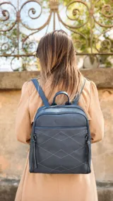 Mochila de diseño estructurado en color bordó, confeccionada en símil cuero con costuras decorativas en forma de rombos en el frente. Cuenta con un bolsillo frontal con cierre, asa superior de mano y correas regulables.