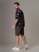 Camisa de manga corta Calvin Klein con corte relaxed fit, confeccionada en algodón regenerativo. Presenta un estampado floral en tonos blanco y gris sobre fondo negro, cierre frontal con botones y un bolsillo de parche en el pecho con el logo de la marca bordado.