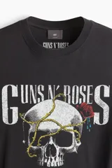 Remera negra de algodón de peso medio, corte holgado (Loose Fit), con cuello redondo. Estampado frontal con el logo de Guns N' Roses, una calavera con una rosa y una cadena, y el texto "Appetite for Destruction 1987-1988".