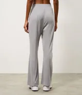 Pantalón deportivo femenino Get Over de corte flare, confeccionado en microfibra de color gris. Presenta cintura con pretina fija, diseño acampanado desde la rodilla y costuras decorativas frontales.