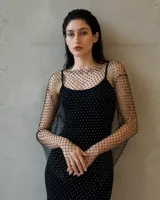 Vestido largo negro de silueta ajustada con aplicación de strass brillante y mangas amplias de red transparente. Incluye una pieza interior básica de color negro.