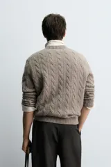 Jersey de punto con diseño de trenzas verticales, cuello redondo y manga larga. Presenta un ajuste regular y acabados en rib en cuello, puños y ruedo.