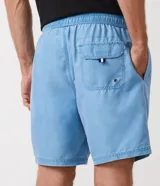 Bermuda de baño masculina en microfibra celeste con efecto lavado, cintura elástica con cordón de ajuste, bolsillos laterales y un bolsillo trasero con solapa y ojal metálico de drenaje.