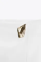 Falda pantalón corta de tiro alto con estampado animal print, cierre lateral oculto y aplique metálico triangular en la parte delantera.