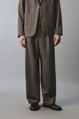Pantalón de traje wide fit color marrón oscuro con textura, pinzas frontales, bolsillos laterales y cierre con cremallera y botón.