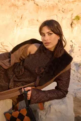 Vestido corto de tejido de punto con lúrex, sin mangas y cuello a la base. Presenta apliques decorativos en forma de flores en el frente y un pequeño tajo en el ruedo.