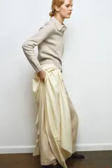 Jersey de lana 100% color beige, con cuello polo, manga larga y botones delanteros.