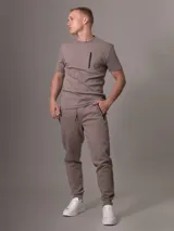 Pantalón de jogging color topo, con cintura elástica ajustable con cordón, puños ajustados y bolsillos laterales con cierre.